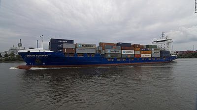 Ein Containerschiff fährt an der Küste entlang.