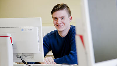 Ein Studierender sitzt an einem Bildschirm.
