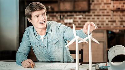 Student am Tisch sitzend mit kleinen Modellwindrädern vor sich