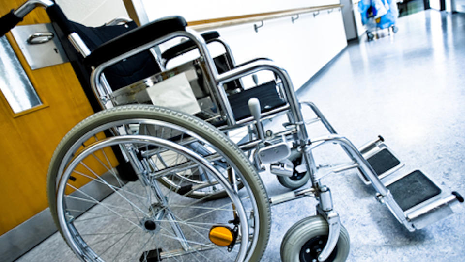 Ein leerer Rollstuhl steht auf einem Gang einer Pflegeeinrichtung.