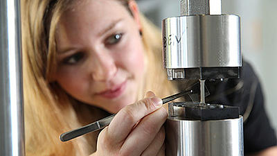 Eine Werkstoffwissenschaftlerin untersucht ein Materialstück.