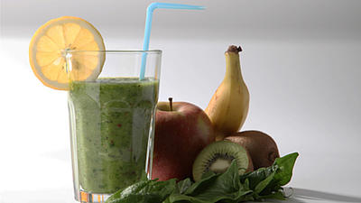 Auf einer hellen Oberfläche steht ein Glas mit einem grünen Smoothie.