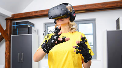 Frau steht mit einer Virtual Reality Brille in einem Raum und testet deren Funktionen