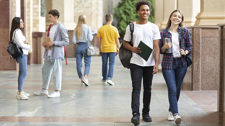 Gut gelaunte Studierende laufen auf dem Campus 