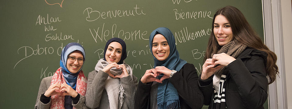 Vier Studierende zeigen Herzen mit ihren Händen.