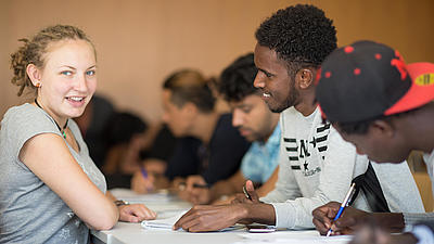 Mehrere Studierende sitzen an einem Tisch.