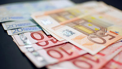 Auf einer dunklen Fläche liegen aufgefächert Geldscheine. Es handelt sich um 20 Euro-Scheine und 10 Euro-Scheine, darauf liegen 50 Euro-Scheine.