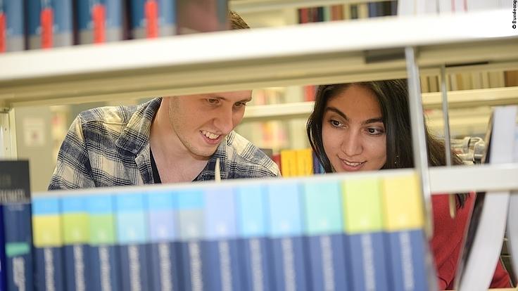 Eine Studentin und ein Student lernen in einer Universitätsbibliothek.