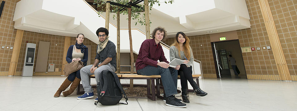 Vier Studierende sitzen auf einer Bank.