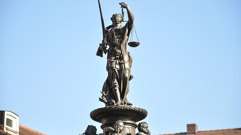 Eine Statue der Göttin Iustitia vor blauem Himmel.