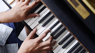 Blick auf Hände, die Klavier spielen.