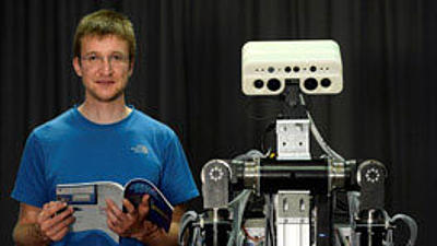 Ein Mann und ein Roboter stehen nebeneinander.