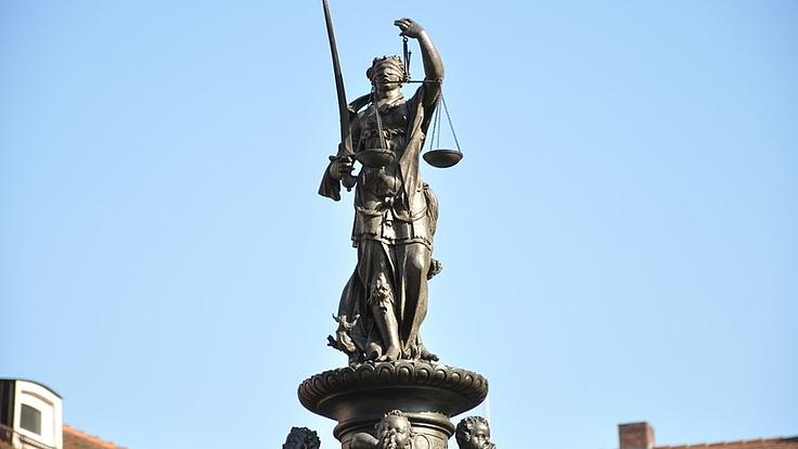 Aufnahme einer Justitia-Statue vor blauem Himmel.