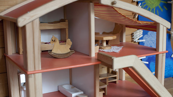 Aufnahme von einem Puppenhaus mit vier verschiedenen Zimmern, bestückt mit wenigen Puppenhausmöbeln.