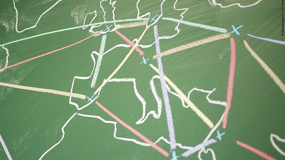Auf einer Schultafel ist eine Weltkarte mit vielen Vernetzungslinien aufgezeichnet