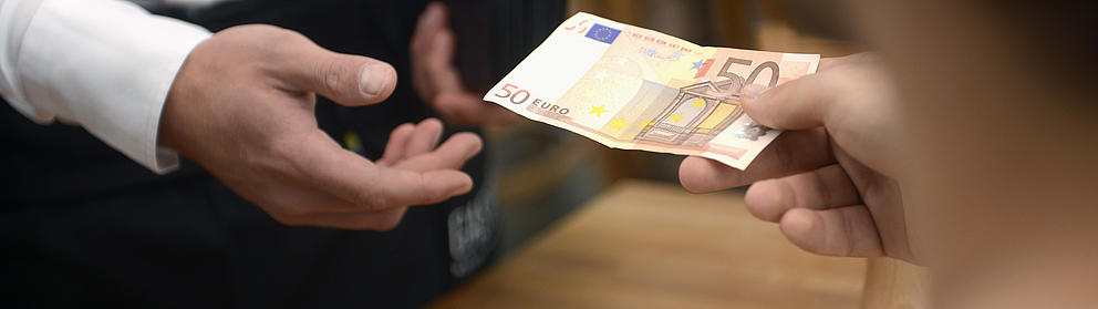 Gäste bezahlen in einem Restaurant mit einem 50-Euro-Schein.
