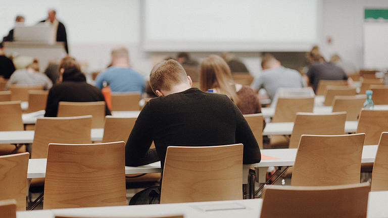 Studenten sitzend im Hörsaal am Lernern und Schreiben