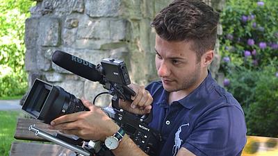 Julian Dagistan hält eine Filmkamera