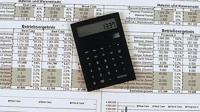 Auf einer ausgedruckten Statistik liegt ein schwarzer Taschenrechner dessen Display die Zahl 1337 zeigt.