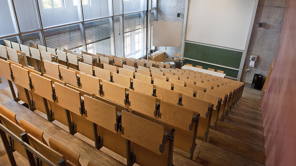 Blick von oben, aus den Sitzreihen, auf einen leeren Vorlesungssaal.