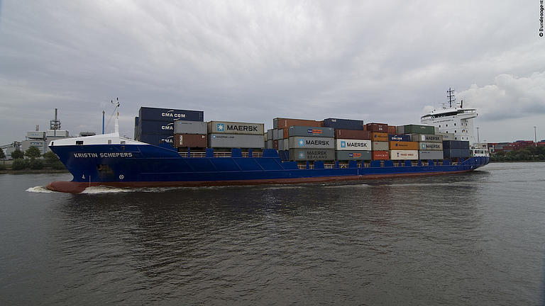 Ein Containerschiff fährt an der Küste entlang.
