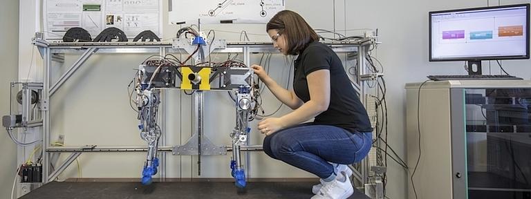 Eine junge Frau nimmt Einstellungen an einem Roboter vor.