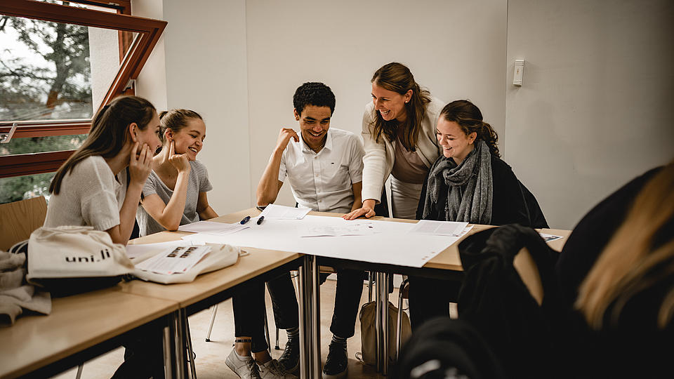 Studenten sitzend an einem Tisch und sprechend über einen Plan, der vor ihnen auf dem Tisch liegt