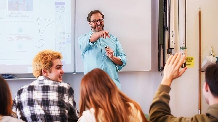 Ein Lehrer ruft einen Schüler auf, der sich meldet.