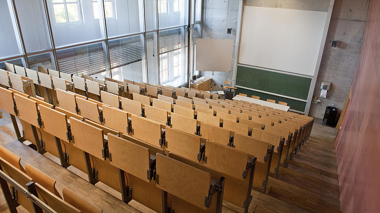 Blick von oben, aus den Sitzreihen, auf einen leeren Vorlesungssaal.