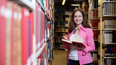 Eine Studentin liest ein Buch in einer Bibliothek.